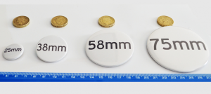 photo showing relative badges sizes to a £1 coin